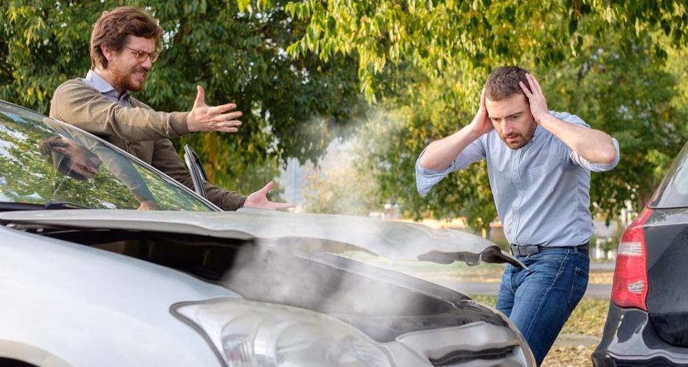 This image shows two men flustered after seeing damages done to their vehicles in a car accident in Springdale, Arkansas