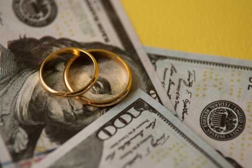 Two wedding rings lying on top of money.