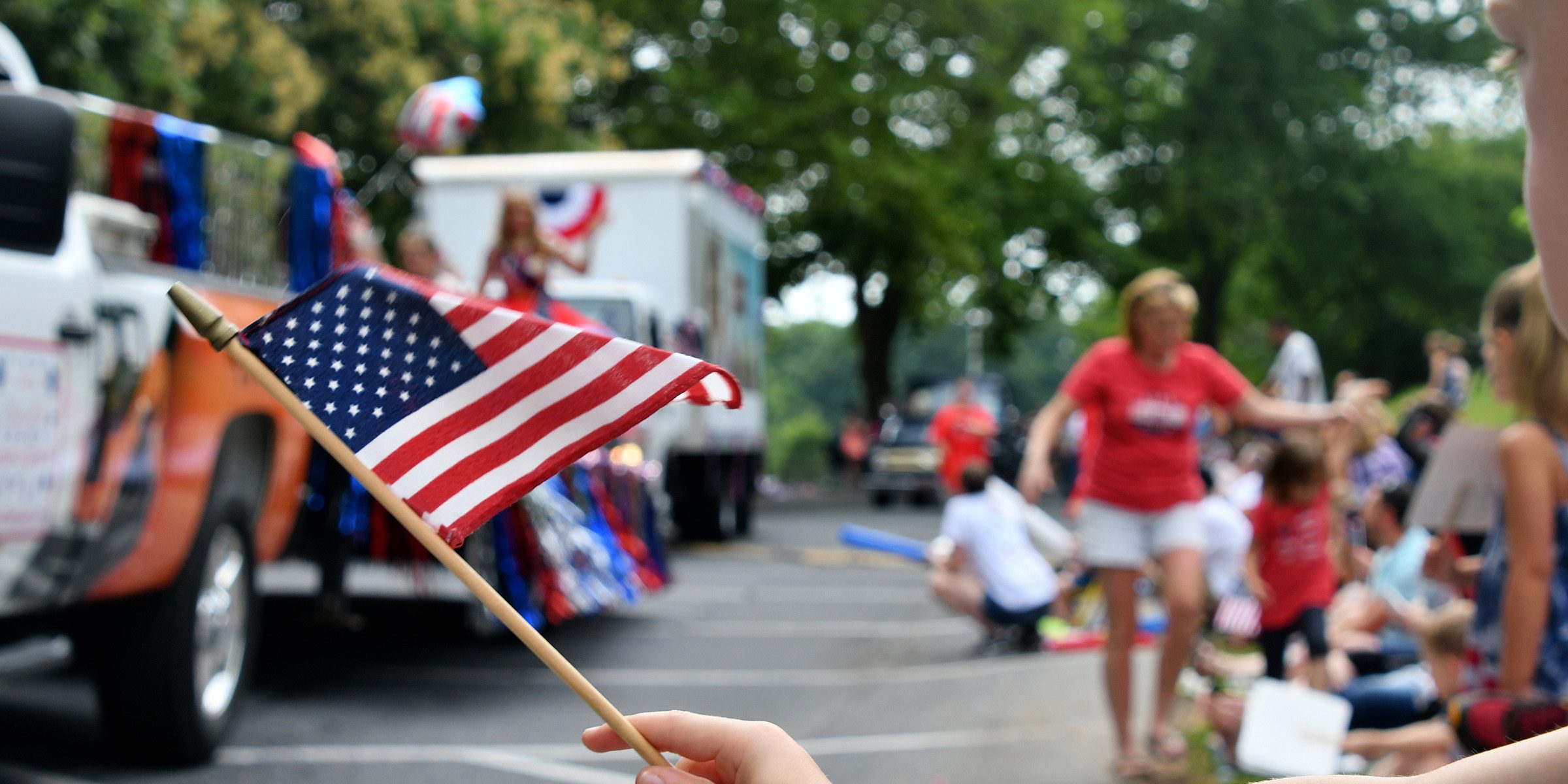 American flag waving in front of fourth of July parade