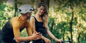 Couple stopping on a bike ride along a tree-lined street to look at cell phone
