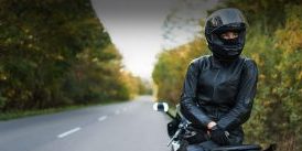 Motorcyclist resting on their bike on the side of a county road